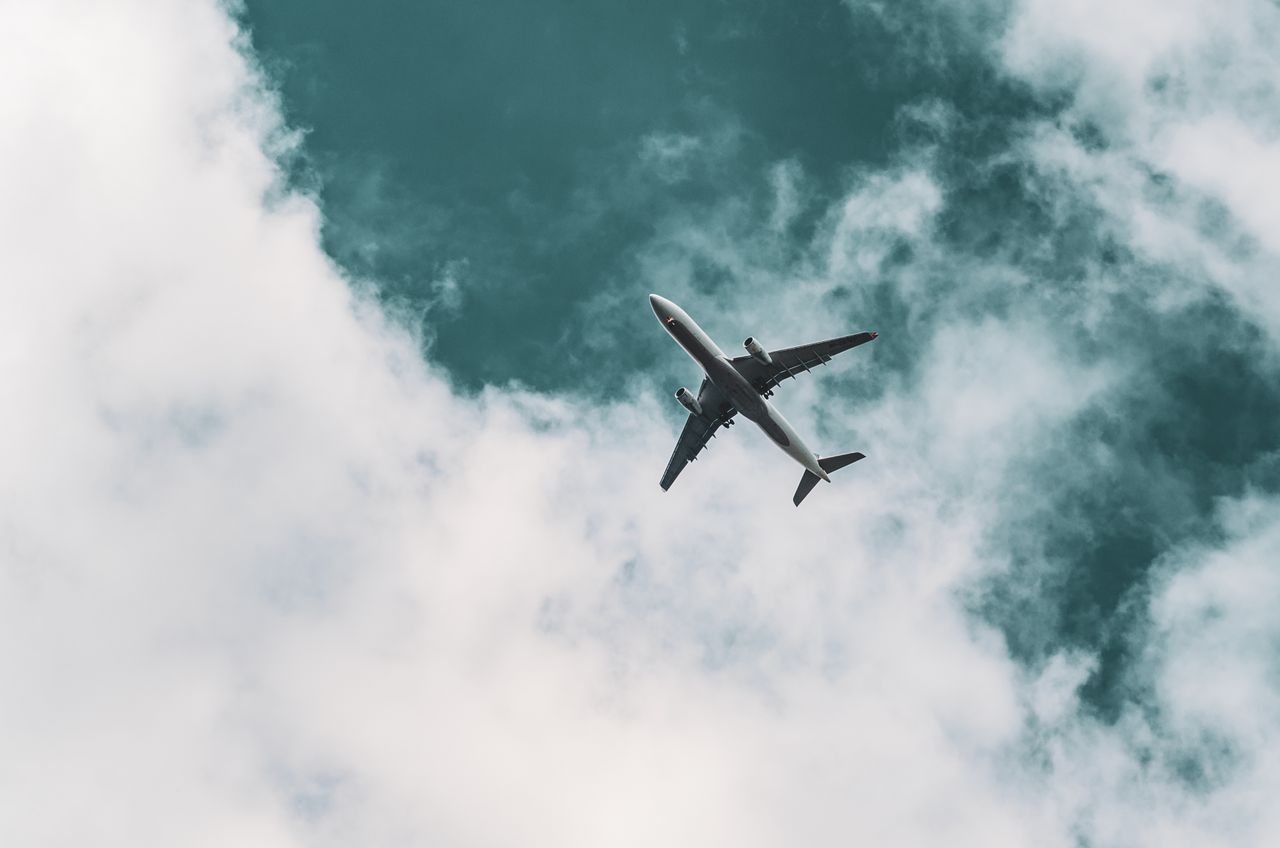 services-01 A commercial airplane gracefully flying through a dynamic cloudy sky, capturing travel essence.