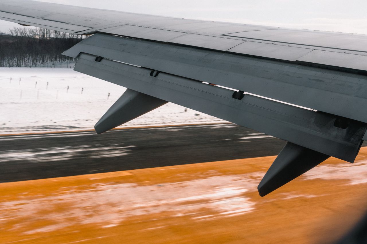 gallery-1 Close-up of an airplane wing during landing on a snowy runway, showcasing aviation dynamics.