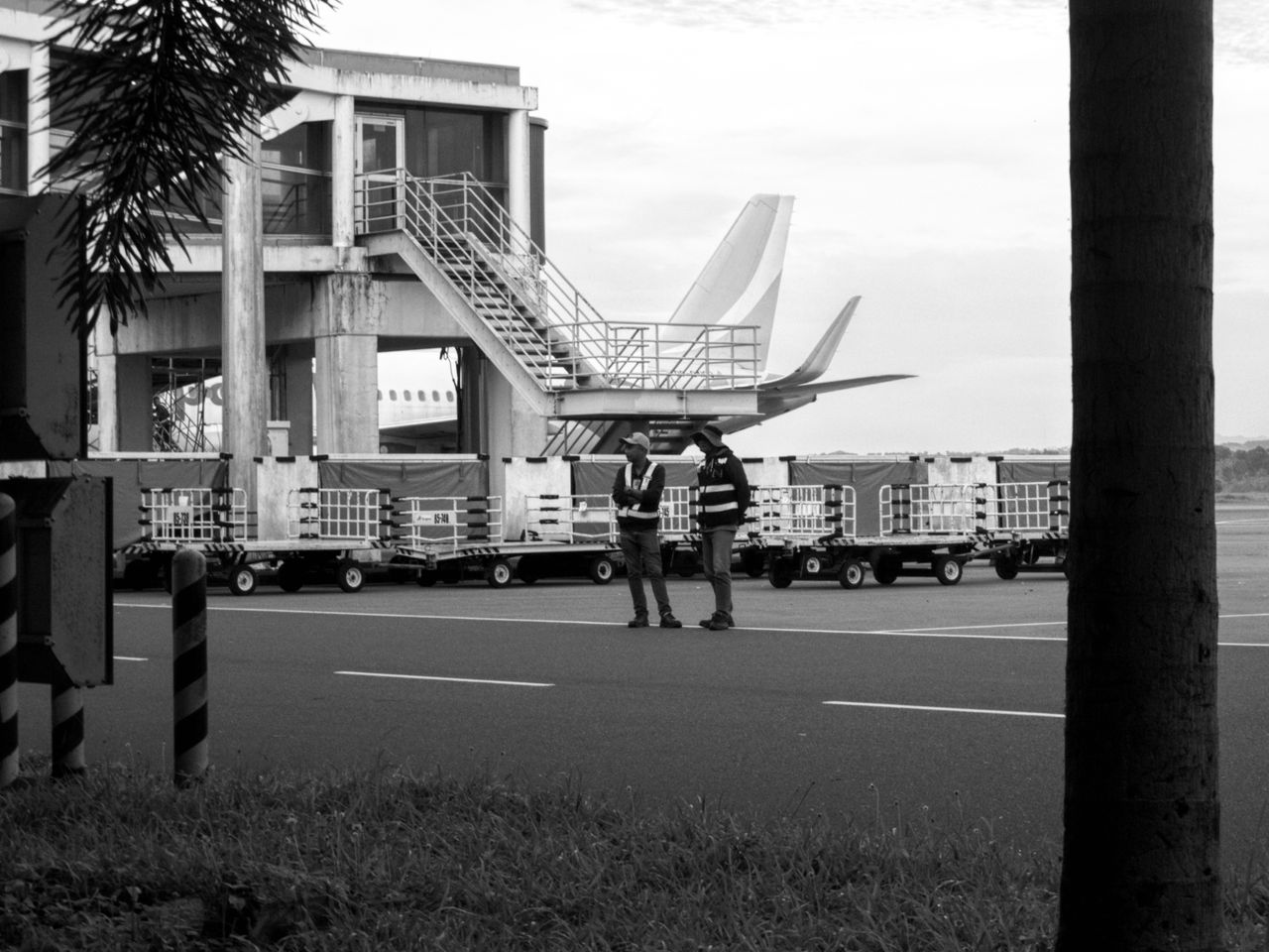 hero-img-01 Two workers discussing logistics at an airport tarmac. Black and white image.