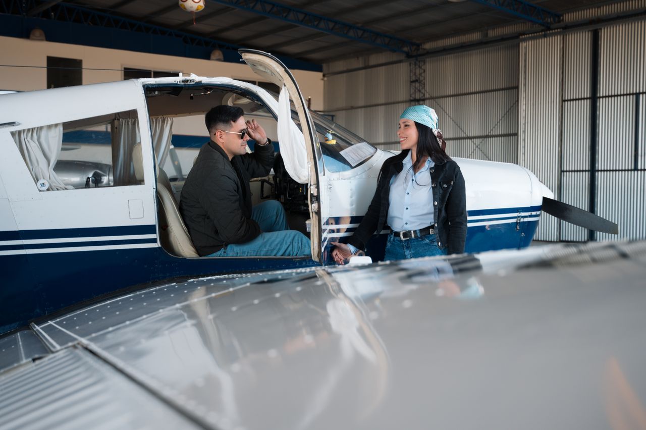 hero-img-02 A man and woman engage in conversation by a small aircraft inside a hangar.
