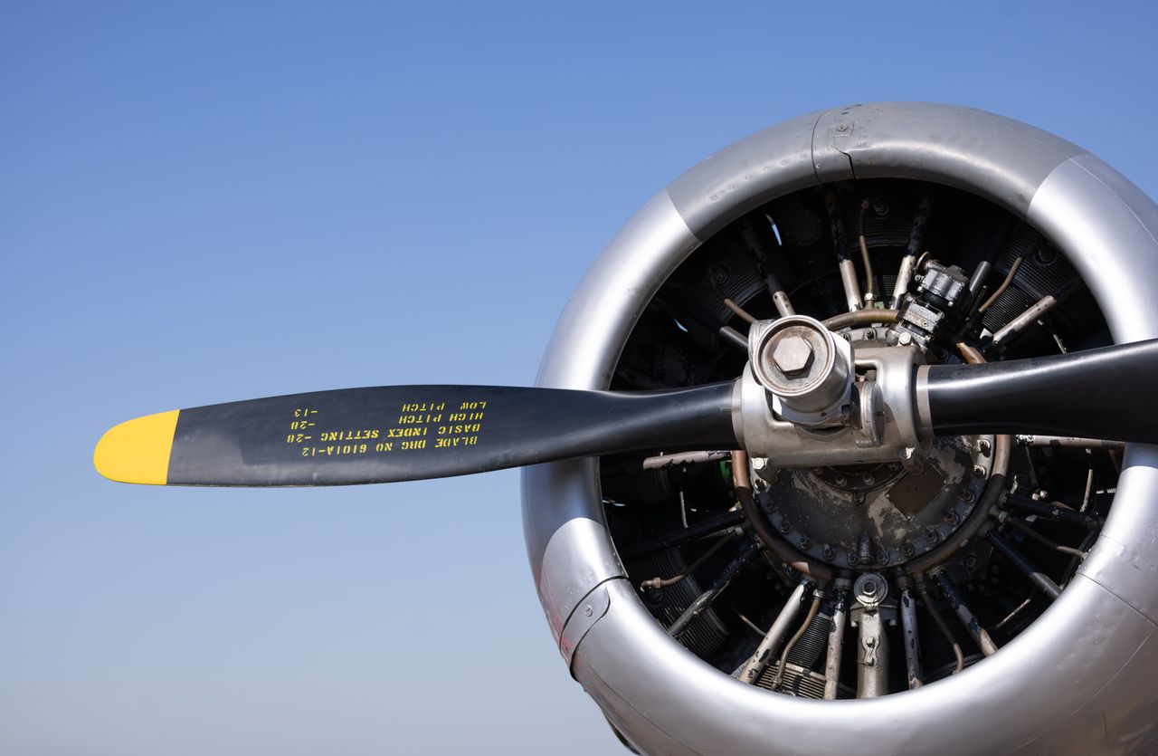 services-03 Detailed view of a classic airplane propeller with visible text under a clear blue sky.